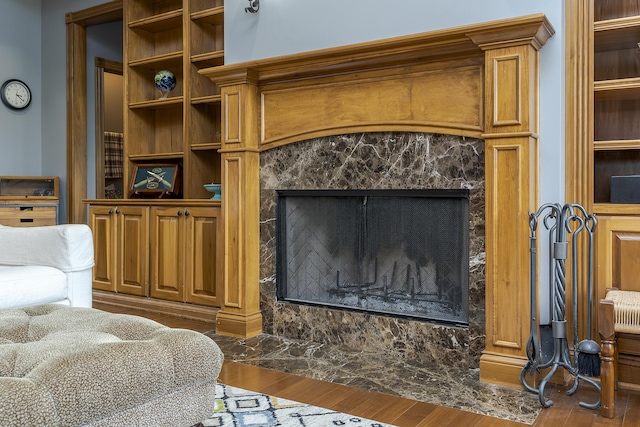 living area featuring a high end fireplace, built in features, and wood finished floors