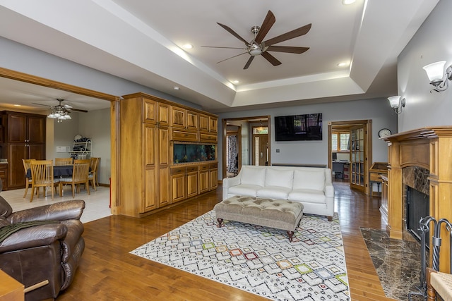 living area featuring a high end fireplace, a ceiling fan, and wood finished floors