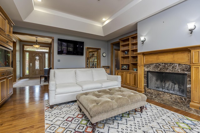 living room with a fireplace, recessed lighting, a raised ceiling, and hardwood / wood-style floors