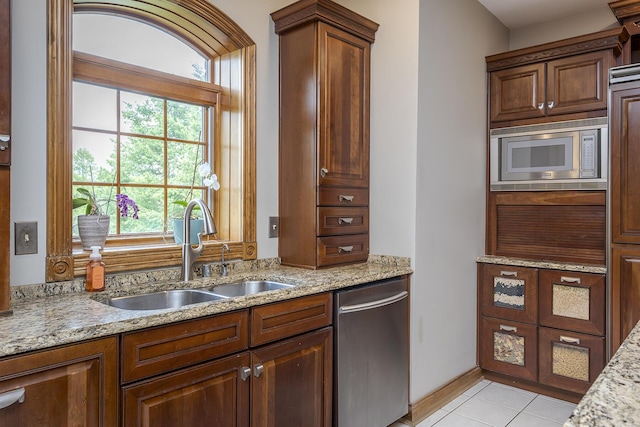 kitchen with a sink, light stone counters, and stainless steel appliances