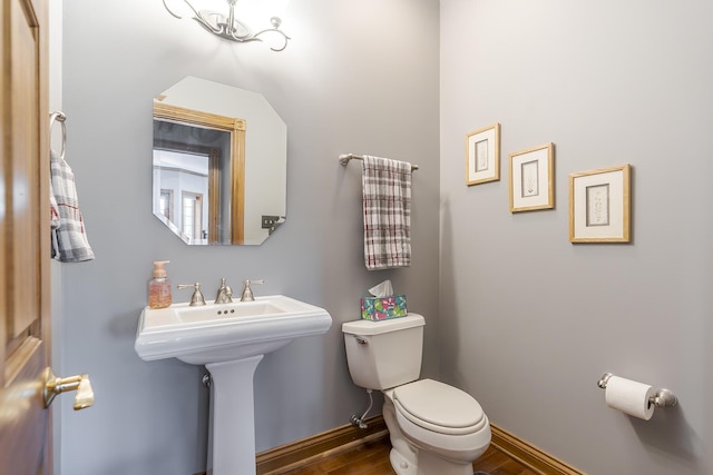 half bath featuring toilet, baseboards, and wood finished floors