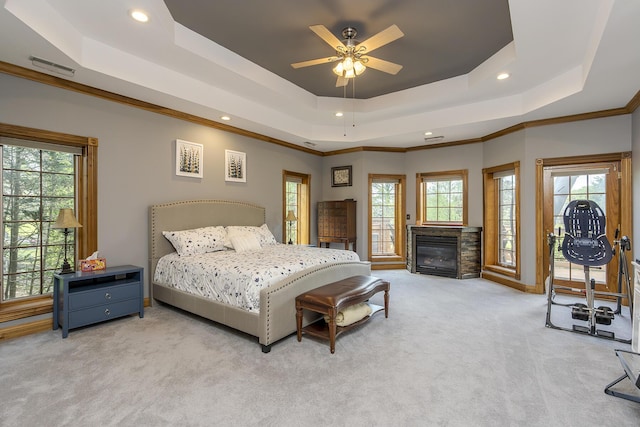 bedroom with recessed lighting, carpet flooring, a raised ceiling, and a glass covered fireplace