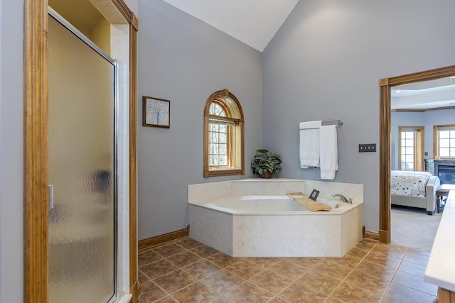 ensuite bathroom with a garden tub, a shower stall, high vaulted ceiling, baseboards, and ensuite bathroom