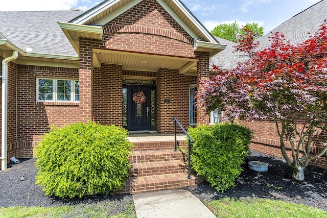 property entrance featuring brick siding and a shingled roof