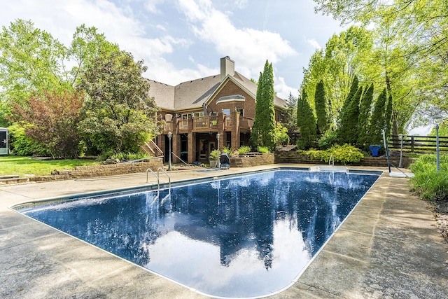 outdoor pool with fence and a wooden deck