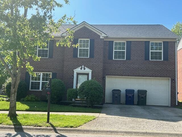 view of front facade with brick siding, a garage, driveway, and a front yard