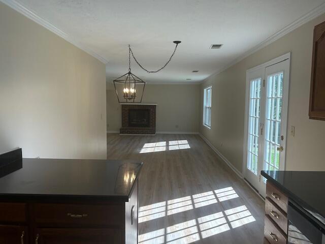 unfurnished dining area with crown molding, baseboards, wood finished floors, and visible vents