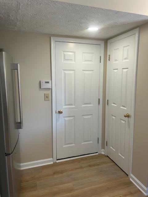 entryway featuring a textured ceiling, baseboards, and light wood finished floors