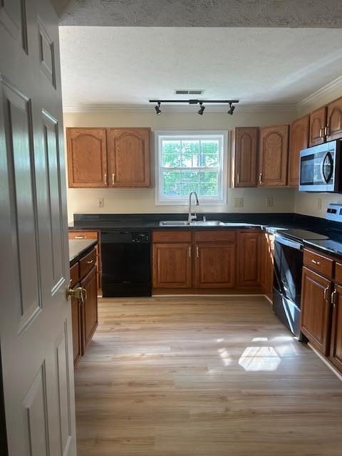 kitchen featuring range with electric cooktop, dark countertops, a sink, stainless steel microwave, and black dishwasher