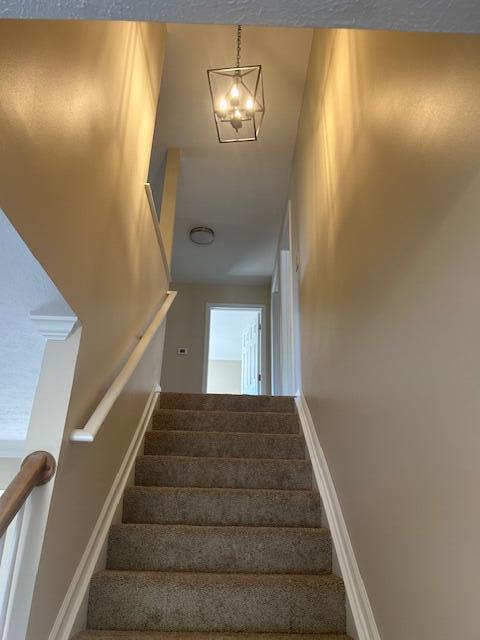 staircase with baseboards and a notable chandelier