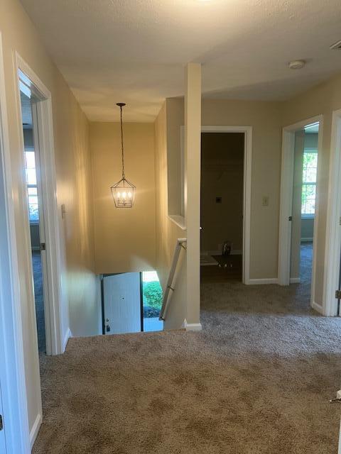 interior space with baseboards, visible vents, carpet flooring, and an upstairs landing