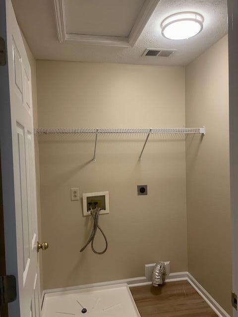 clothes washing area featuring laundry area, hookup for a washing machine, wood finished floors, hookup for an electric dryer, and visible vents