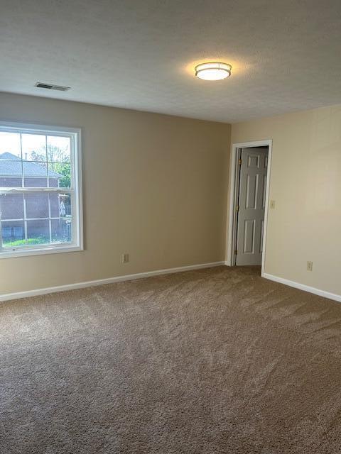 unfurnished room with dark colored carpet, baseboards, and visible vents