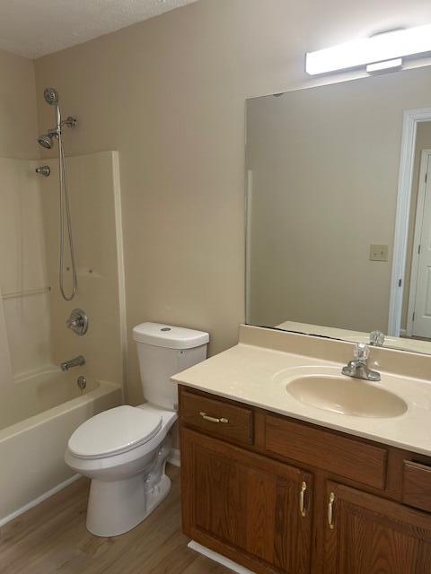 full bath featuring vanity, shower / bathtub combination, wood finished floors, and toilet