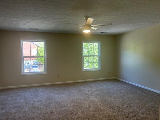 spare room with a textured ceiling, baseboards, a ceiling fan, and carpet floors