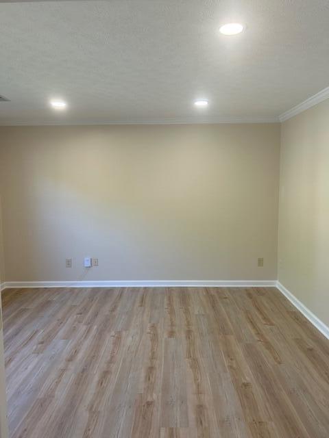 spare room with baseboards, recessed lighting, light wood-style floors, and ornamental molding