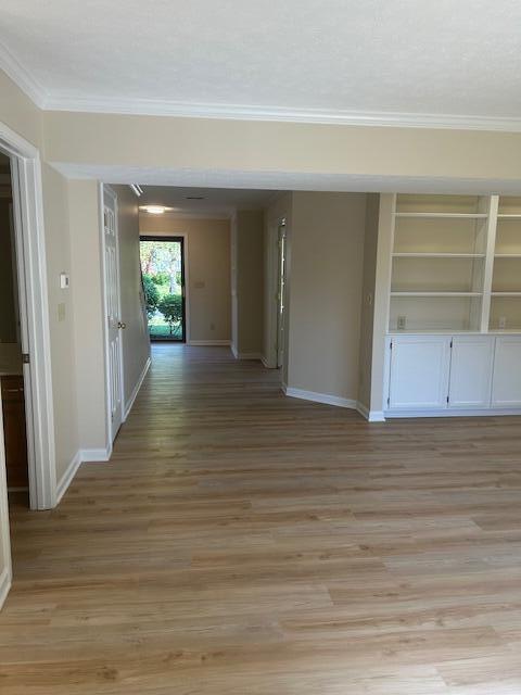 hall featuring baseboards, ornamental molding, and light wood-type flooring