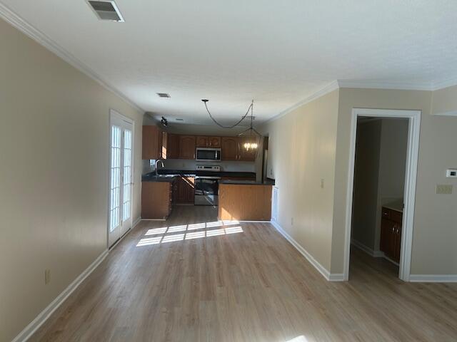 kitchen with dark countertops, stainless steel microwave, wood finished floors, and visible vents