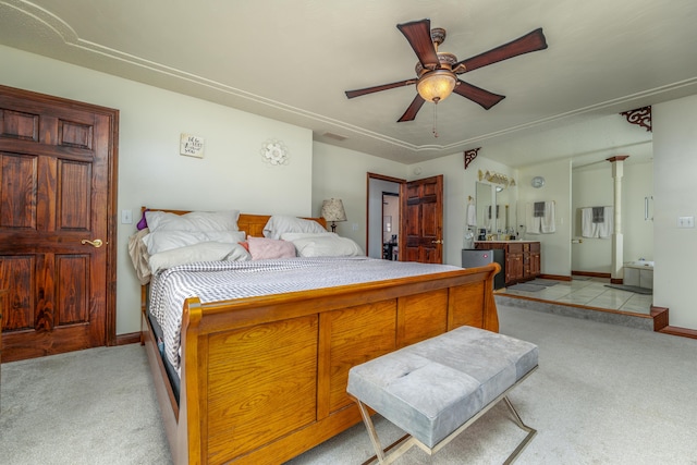 bedroom featuring light colored carpet, baseboards, a ceiling fan, and ensuite bath