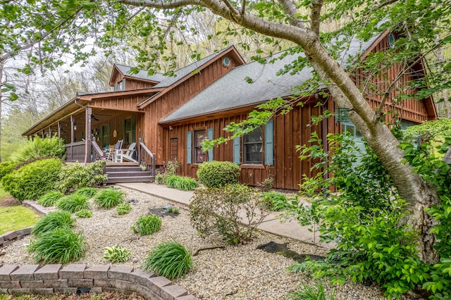 rear view of property featuring covered porch, a ceiling fan, roof with shingles, and board and batten siding