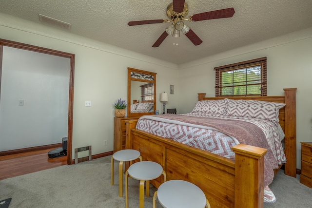 carpeted bedroom with a textured ceiling, ceiling fan, and baseboards
