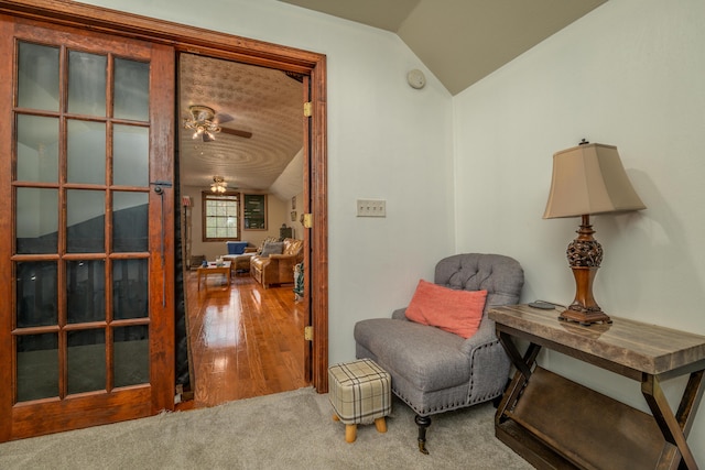 sitting room featuring lofted ceiling, wood finished floors, a ceiling fan, and carpet