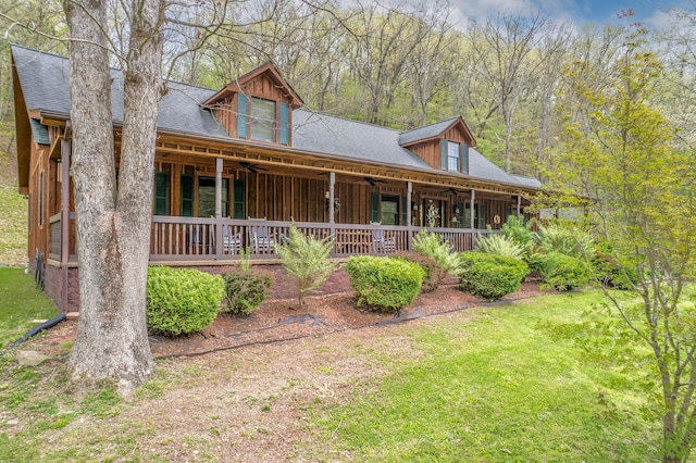 view of front of property featuring a ceiling fan, a front lawn, roof with shingles, and covered porch