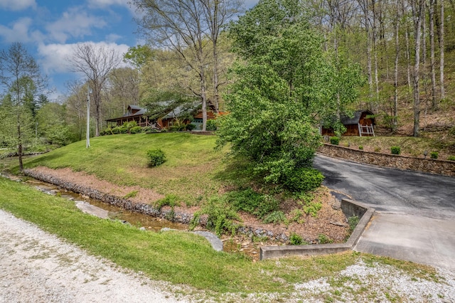 view of front of property featuring asphalt driveway, a front lawn, an outdoor structure, and a barn