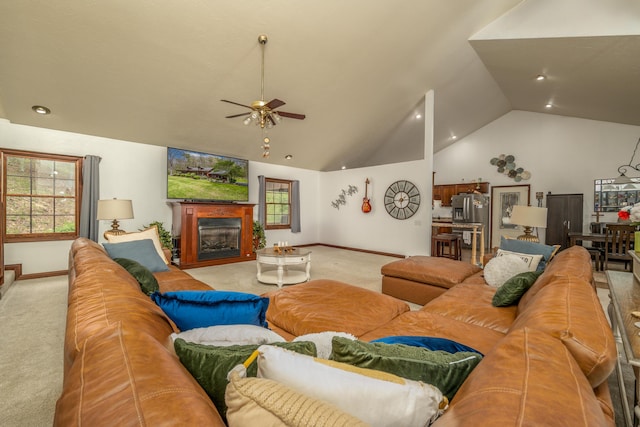living area featuring vaulted ceiling, light colored carpet, a ceiling fan, baseboards, and a glass covered fireplace