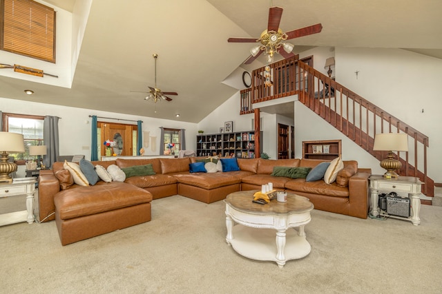 carpeted living area featuring ceiling fan, high vaulted ceiling, and stairs