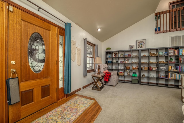entryway with vaulted ceiling, carpet, and baseboards