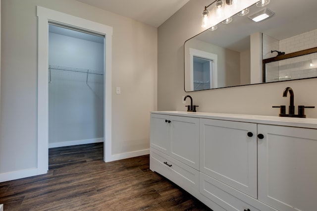 bathroom with baseboards, a sink, wood finished floors, and a tile shower