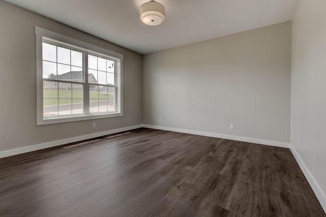 empty room featuring baseboards and dark wood-style flooring