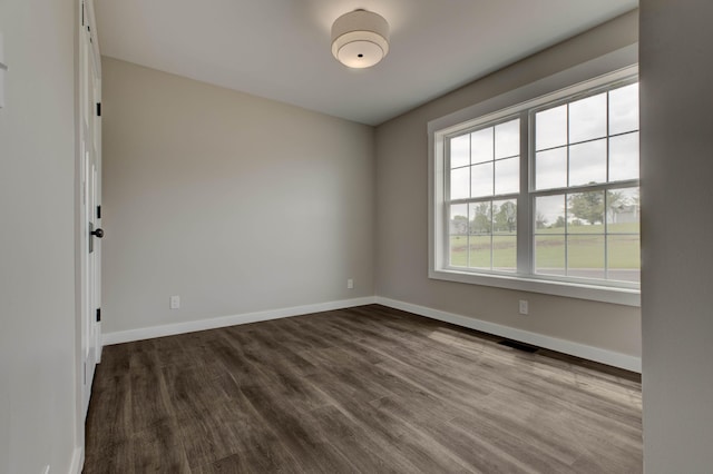 empty room with baseboards, dark wood-style floors, and visible vents