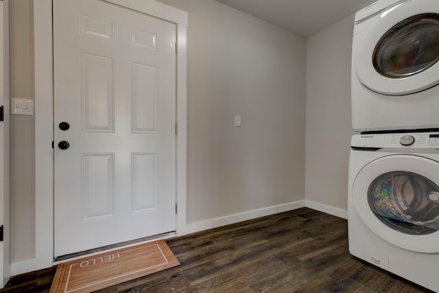 clothes washing area featuring baseboards, laundry area, dark wood finished floors, and stacked washer / dryer