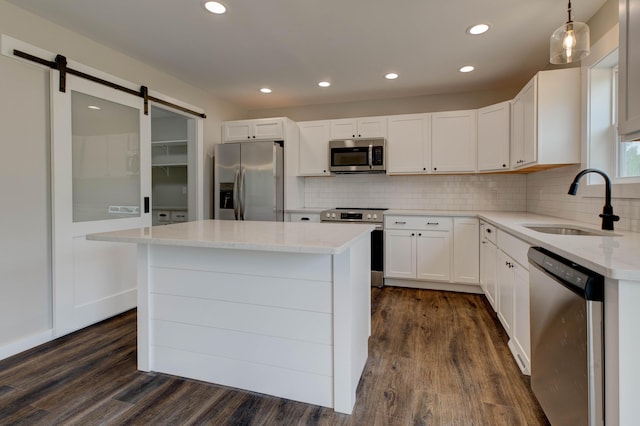 kitchen featuring stainless steel appliances, light stone countertops, dark wood-style floors, and a sink