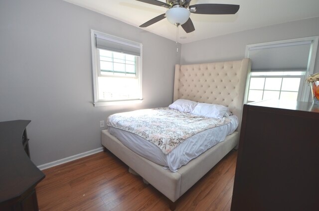 bedroom with a ceiling fan, baseboards, and wood finished floors