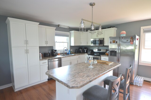 kitchen featuring a kitchen island, dark wood-type flooring, white cabinets, a sink, and stainless steel appliances