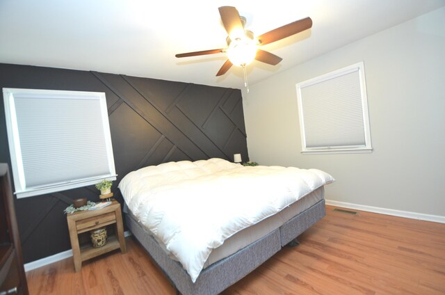 bedroom with visible vents, a ceiling fan, baseboards, and wood finished floors
