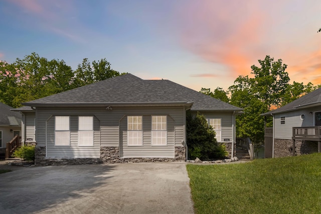 exterior space featuring roof with shingles, a front lawn, and stone siding