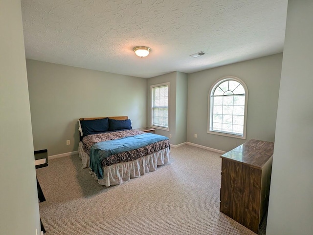 bedroom with visible vents, carpet flooring, baseboards, and a textured ceiling