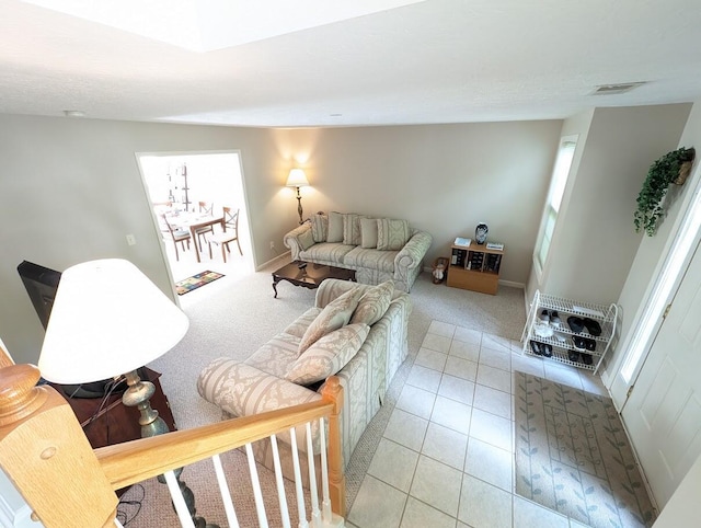 living area with baseboards, light carpet, light tile patterned flooring, and visible vents