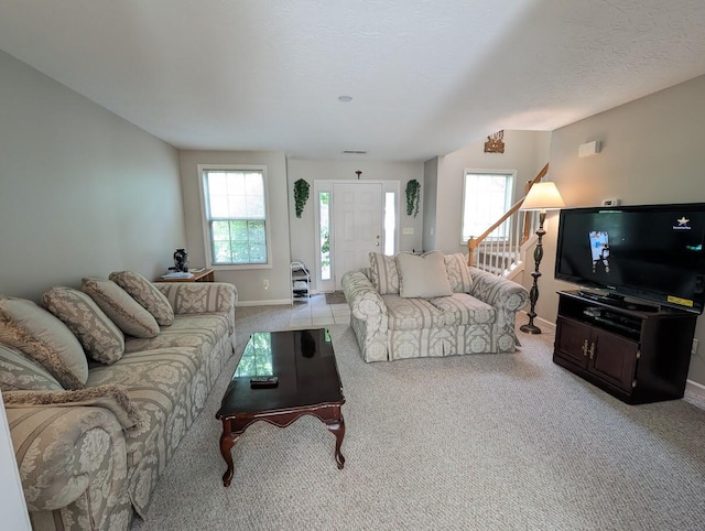 living room featuring baseboards, light colored carpet, and stairway
