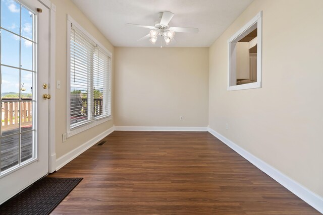 unfurnished room with a ceiling fan, baseboards, and dark wood-style floors