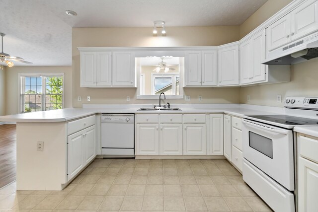 kitchen featuring a sink, a peninsula, white appliances, under cabinet range hood, and a ceiling fan