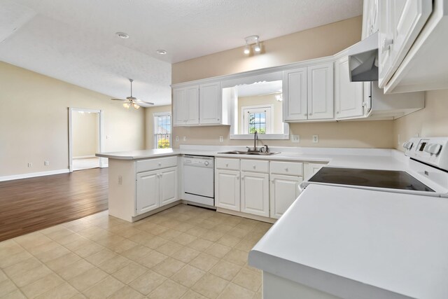 kitchen with a sink, light countertops, a peninsula, and white appliances