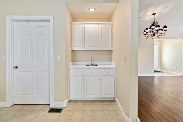 laundry area with visible vents, a sink, baseboards, light tile patterned floors, and a chandelier