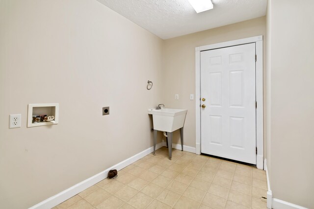clothes washing area with laundry area, baseboards, hookup for a washing machine, a textured ceiling, and hookup for an electric dryer