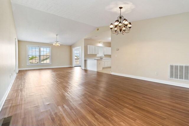 unfurnished living room with baseboards, visible vents, vaulted ceiling, and light wood-style floors