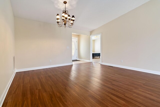 spare room featuring baseboards, visible vents, dark wood-style flooring, and a notable chandelier
